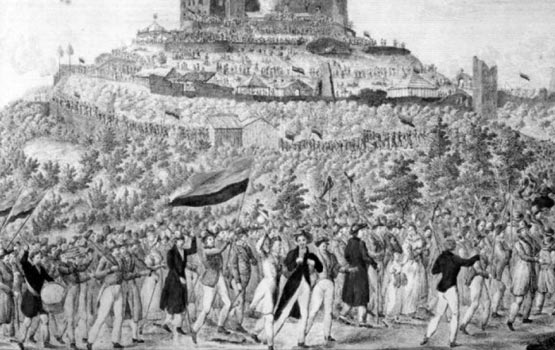 Zug zum Hambacher Fest. – Teilkolorierte Federzeichnung von 1832. Die Flaggen zeigen die damals so gewählten deutschen Landesfarben Gold-Rot-Schwarz.. By Erhard Joseph Brenzinger (Full colored illustration from 1832) [Public domain], via Wikimedia Commons